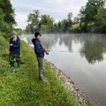 Zwei Jungfischer angeln nebeneinander am dampfenden Wasser